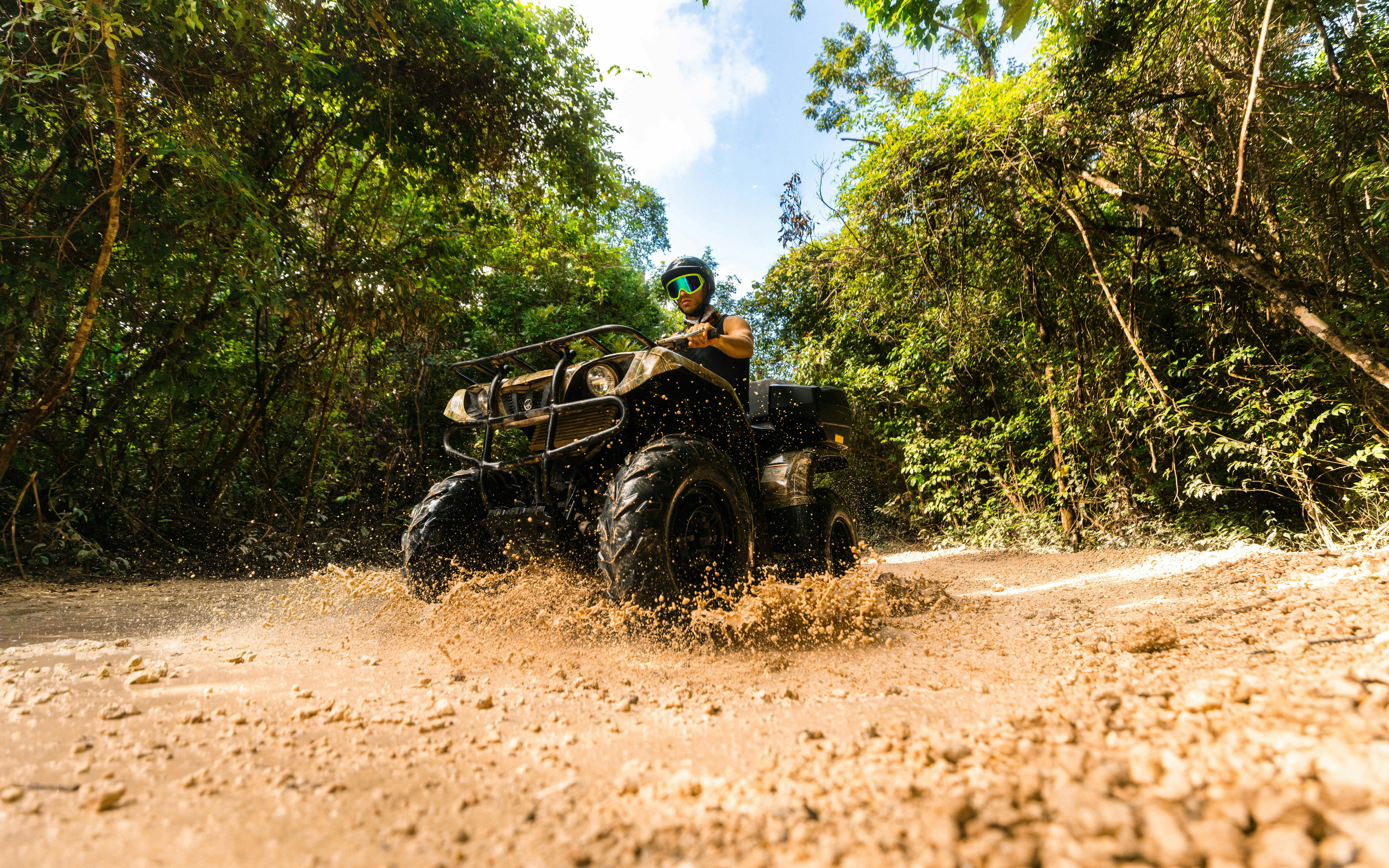 ATV rider navigating muddy trail in Cancun Extreme Adventuring Park.
