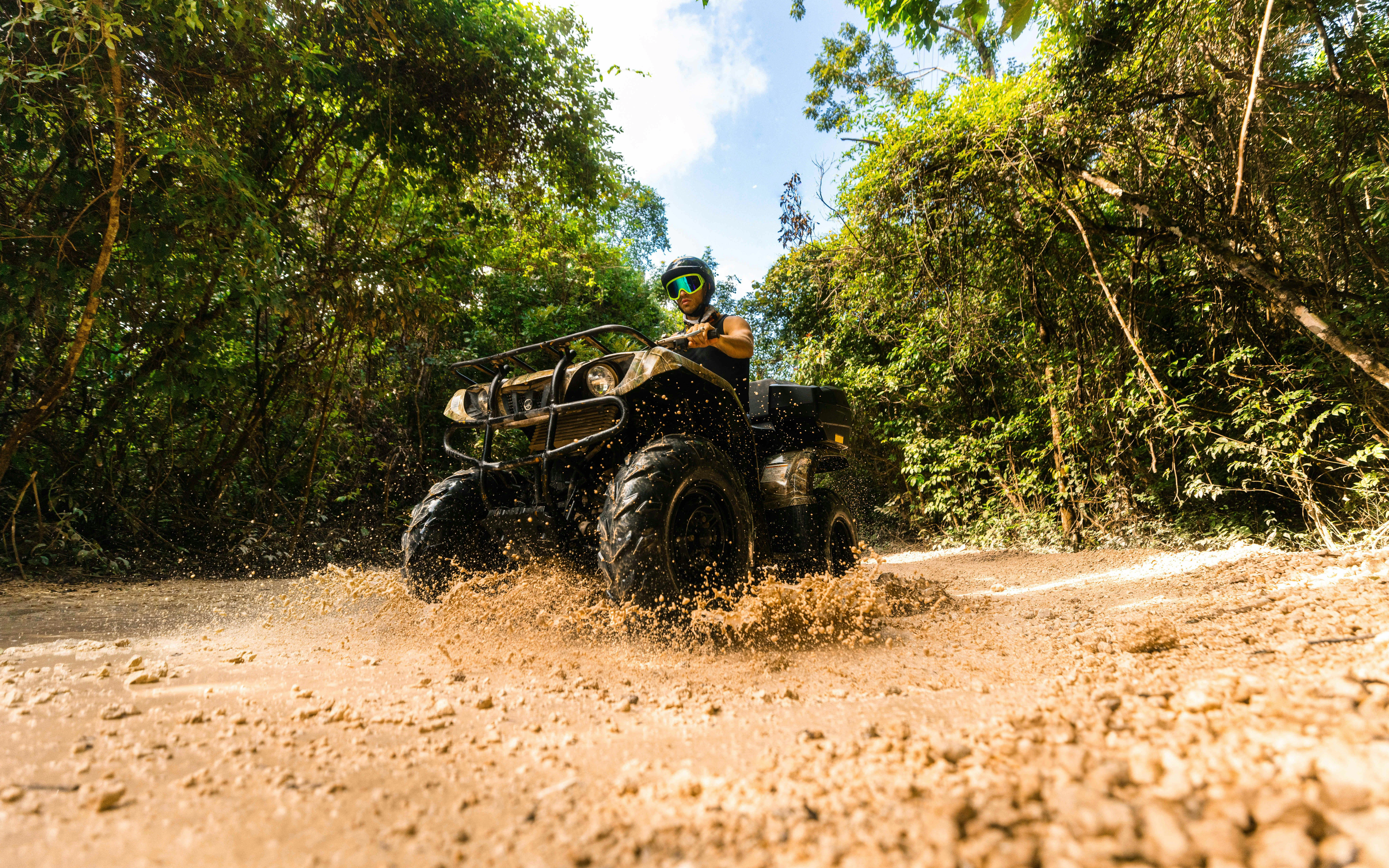 ATV rider navigating muddy trail in Cancun Extreme Adventuring Park.