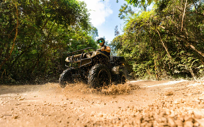 ATV rider navigating muddy trail in Cancun Extreme Adventuring Park.