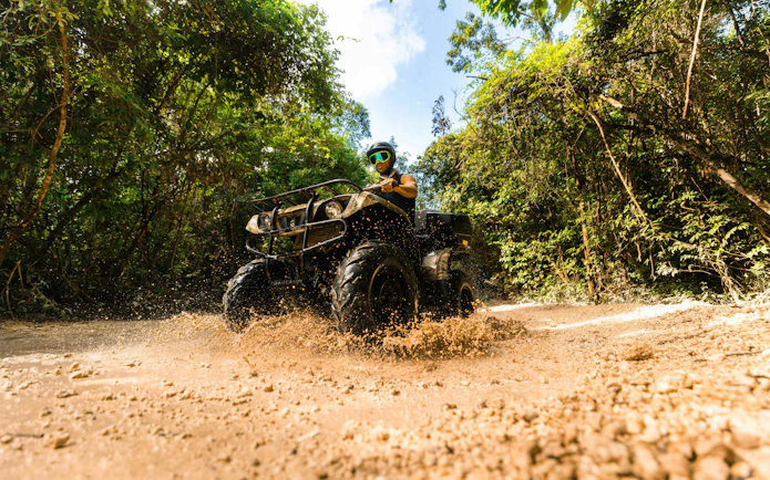 ATV rider navigating muddy trail in Cancun Extreme Adventuring Park.