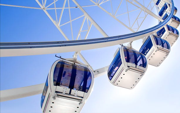 Ferris wheel gondolas on the Wheel of Brisbane against a clear blue sky.