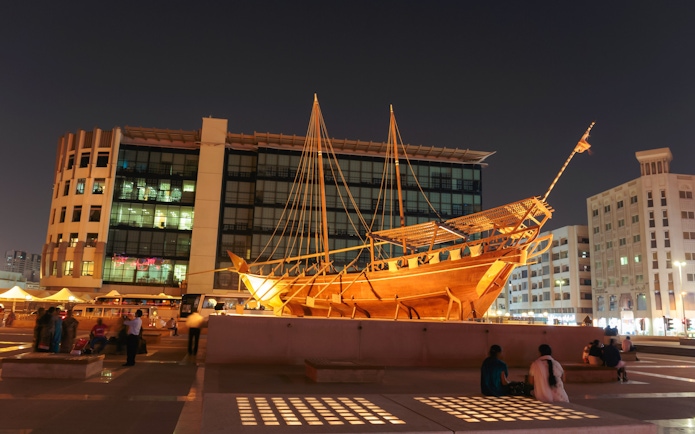 Wooden dhow boat displayed at night near Al Fahidi Fort, Dubai.