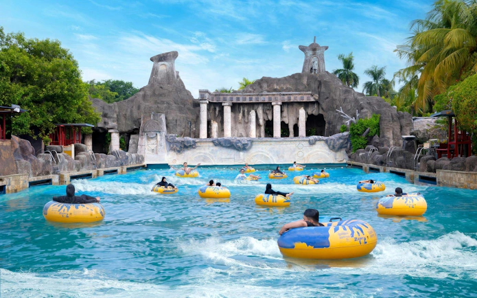 Visitors enjoying wave pool at Atlantis Water Adventure Park Ancol with ancient ruins backdrop.