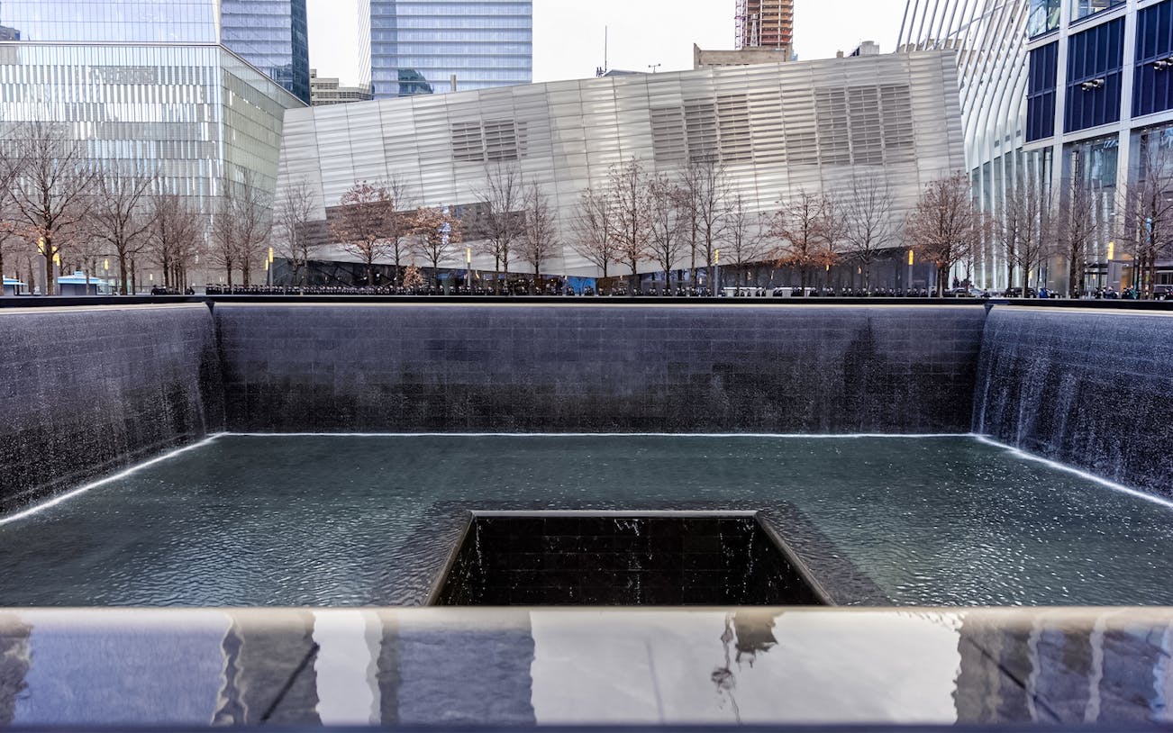 Reflecting pool at 911 Memorial Museum in New York City with surrounding buildings.