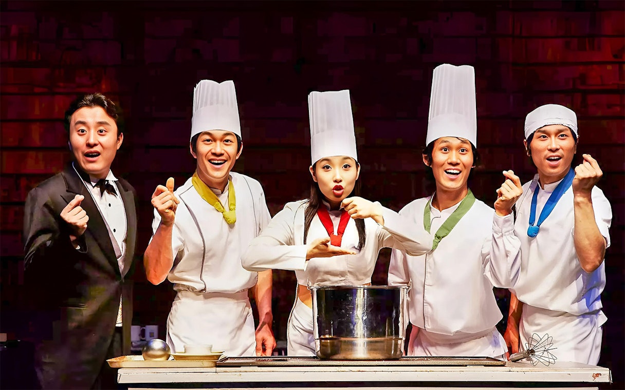 Performers in chef outfits on stage during Jeju Nanta Musical Show.