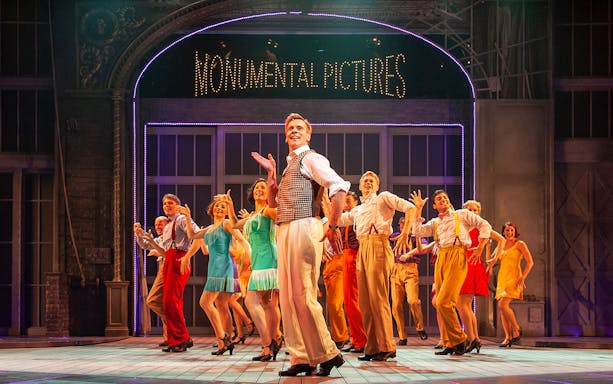 Performers dancing on stage in a scene from "Singin’ in the Rain" musical.