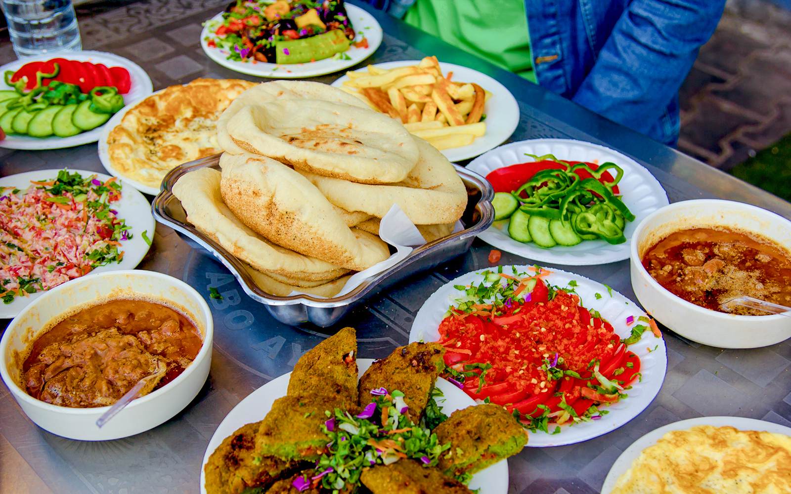 Traditional Egyptian meal with pita bread, falafel, ful medames, and fresh vegetables.