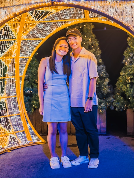 Couple standing under illuminated arches at Gardens by the Bay during Christmas.
