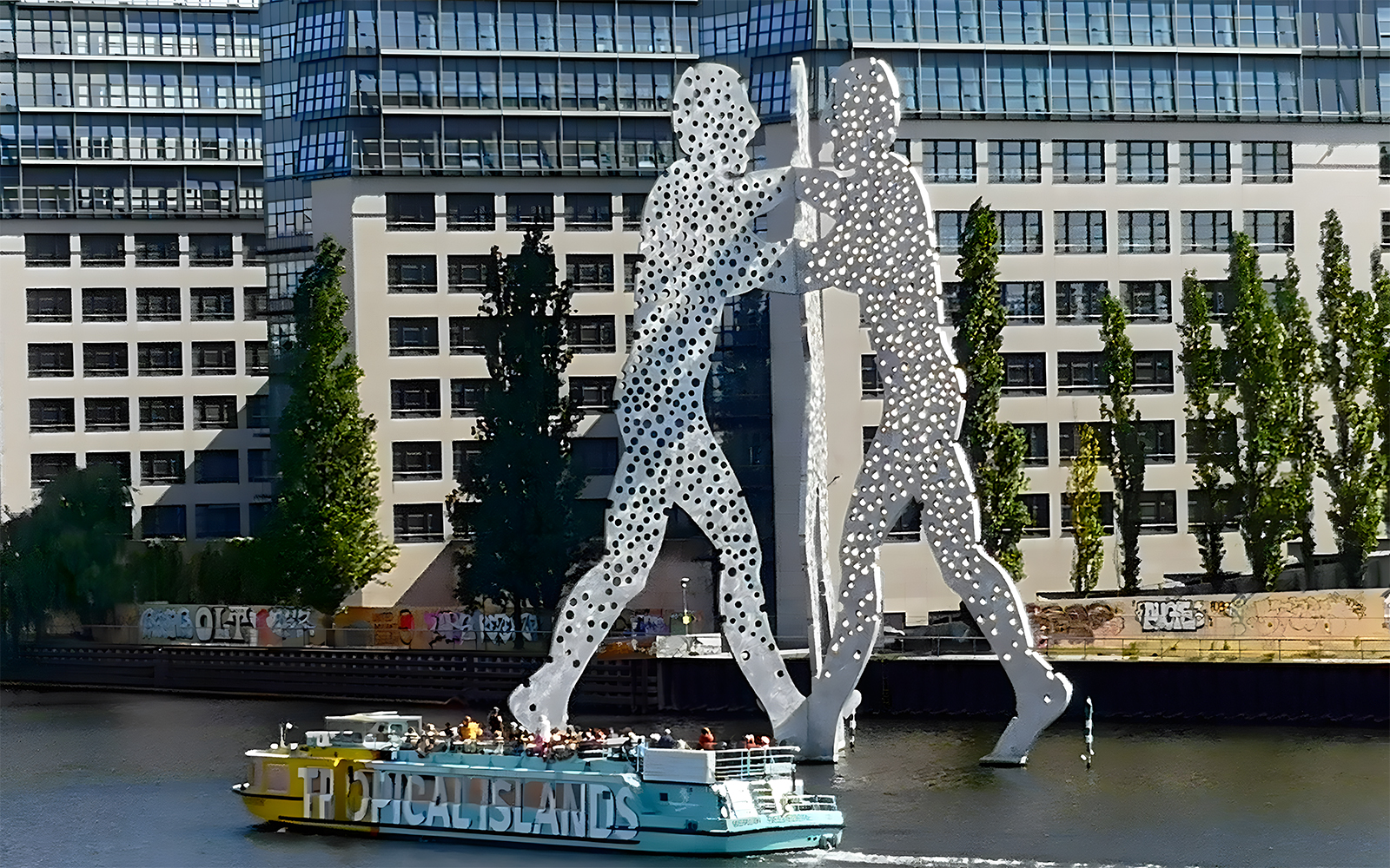 Sightseeing cruise passing the Molecule Man sculpture on the Spree River in East Berlin.