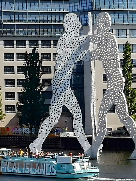 Sightseeing cruise passing the Molecule Man sculpture on the Spree River in East Berlin.