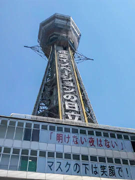 Tsutenkaku Tower in Osaka, Japan, with signage and clear blue sky.