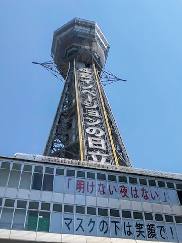 Tsutenkaku Tower in Osaka, Japan, with signage and clear blue sky.