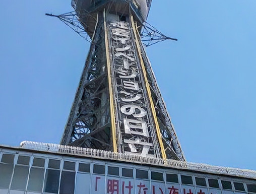 Tsutenkaku Tower in Osaka, Japan, with signage and clear blue sky.