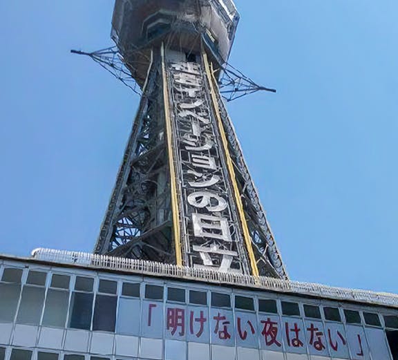 Tsutenkaku Tower in Osaka, Japan, with signage and clear blue sky.
