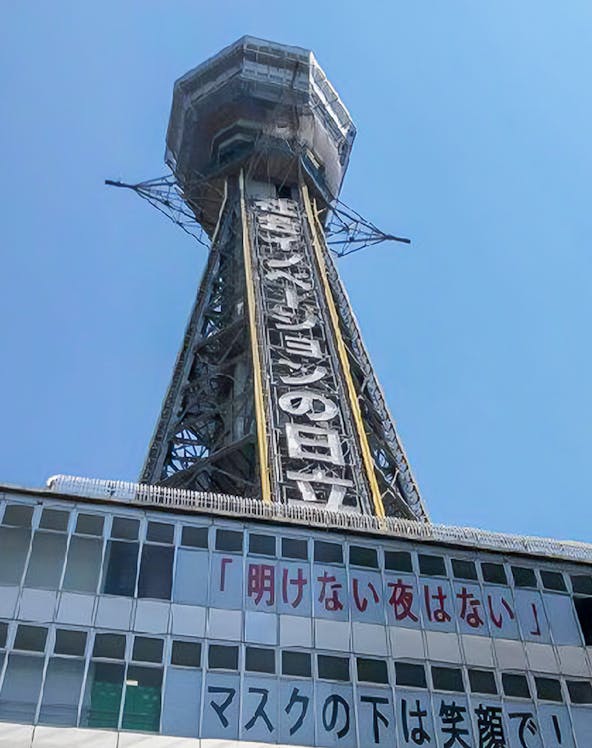 Tsutenkaku Tower in Osaka, Japan, with signage and clear blue sky.