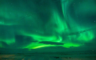 Northern Lights display over snowy landscape, Reykjavik tour.