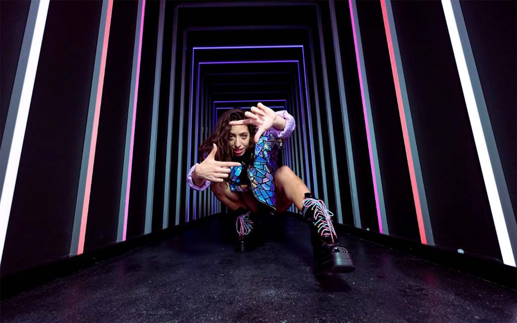 Person posing in a neon-lit tunnel at The Upside Down Berlin.