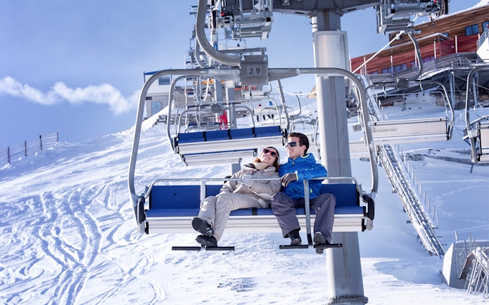 Couple on cable car at Glacier 3000 with snowy mountain backdrop.