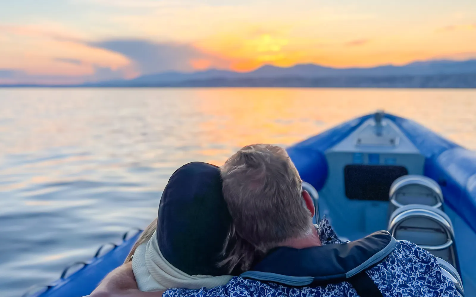 Couple enjoying a sunset boat tour on calm waters.