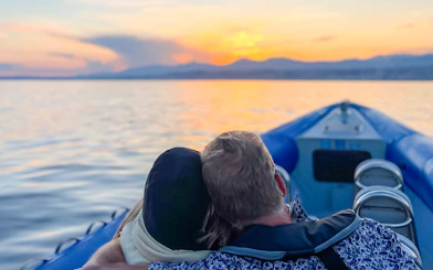 Couple enjoying a sunset boat tour on calm waters.