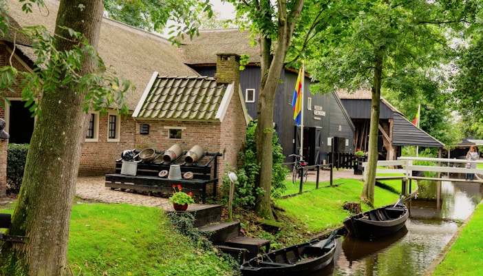 Museum in Giethoorn village center with canal and boats, Netherlands.