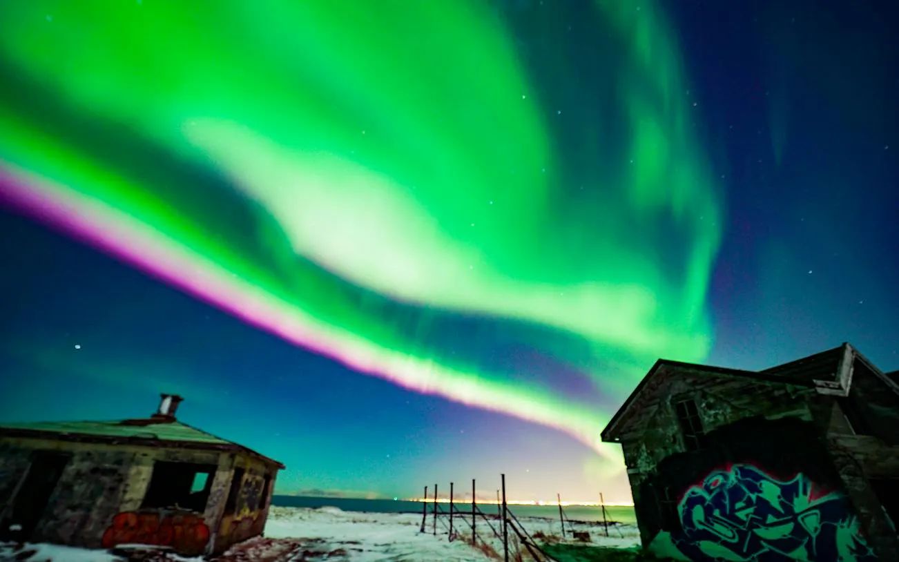 Northern Lights over abandoned buildings with graffiti near Reykjavik during a small-group jeep tour.