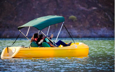 Couple enjoying a pedal boat ride on Hatta Lake during a day trip from Sharjah.