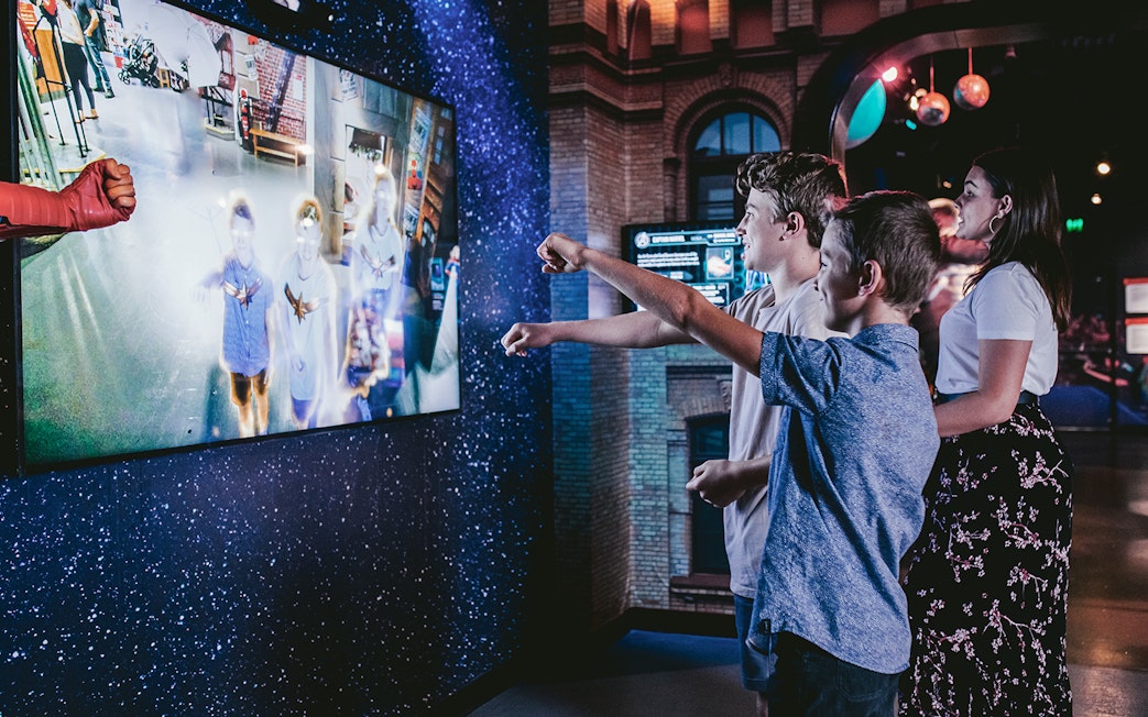 Visitors interacting with a superhero exhibit at Madame Tussauds Sydney.