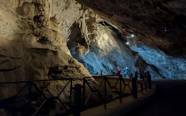 Visitors exploring San Giovanni Caves along Vagoni Path, illuminated rock formations.