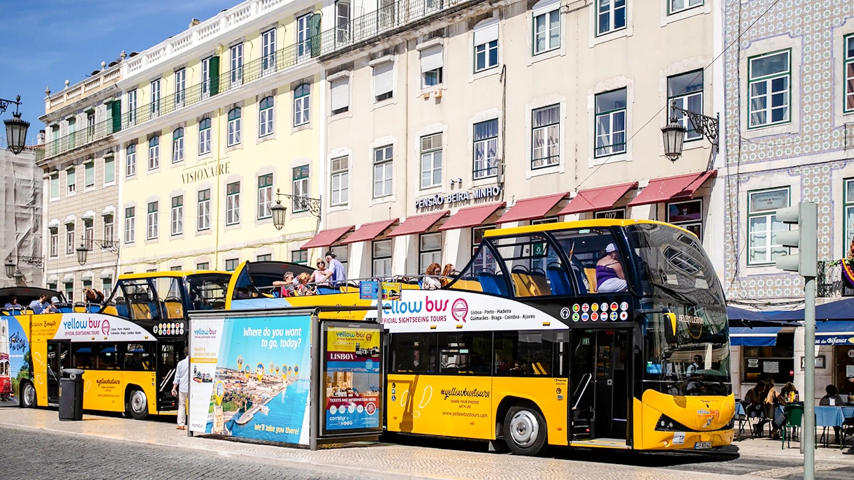 Tourists on a yellow sightseeing bus in Lisbon city center.
