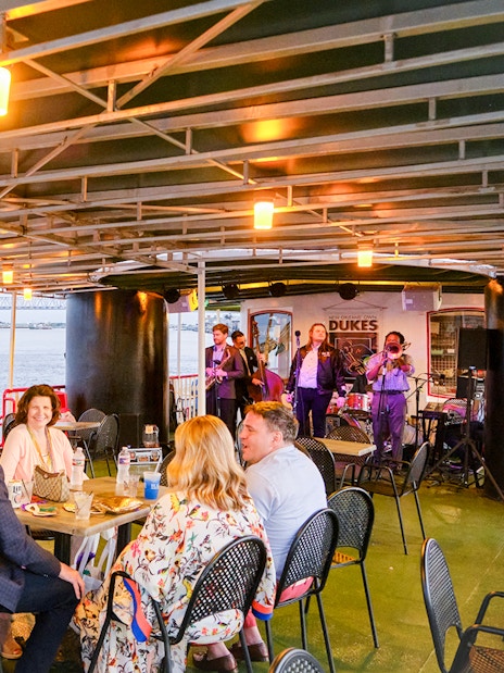 People dining on Steamboat Natchez with live band and river view in New Orleans.
