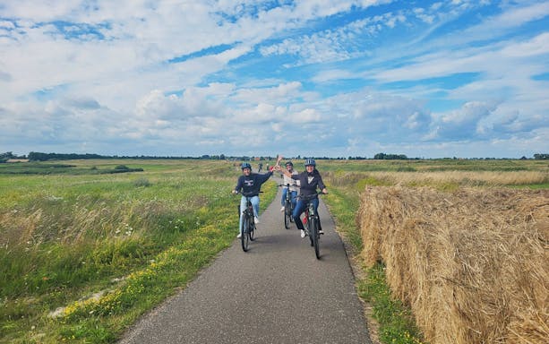 Cyclists on e-bike tour through scenic countryside path.