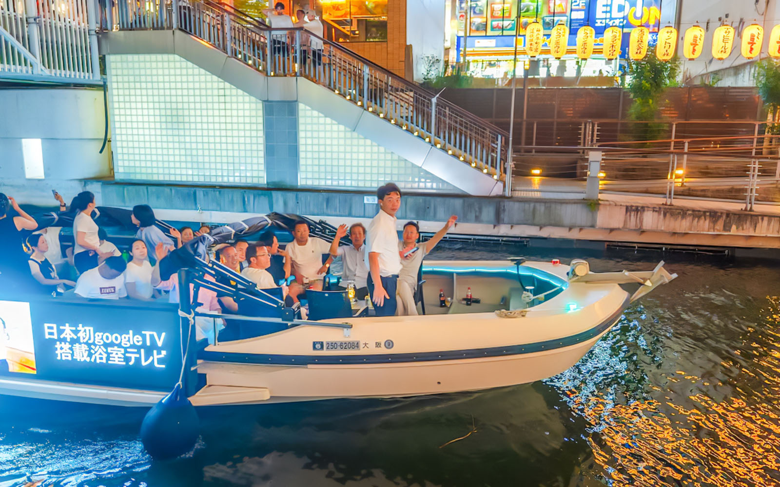 Tourists enjoying a river cruise on Osaka's Dotonbori River at night.