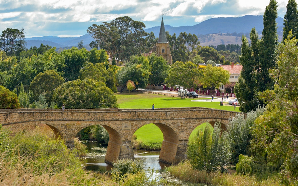 Richmond Bridge in Tasmania with surrounding greenery and distant church.