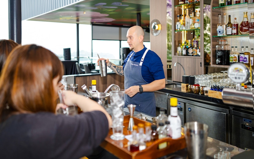 Bartender leading cocktail workshop at Mirabilis bar, Singapore, with cable car view.