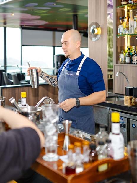 Bartender leading cocktail workshop at Mirabilis bar, Singapore, with cable car view.