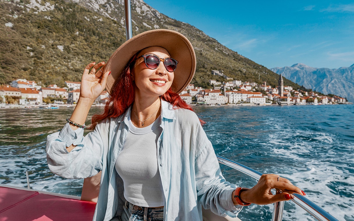 Female guest on a boat trip in Kotor Bay with coastal town view.