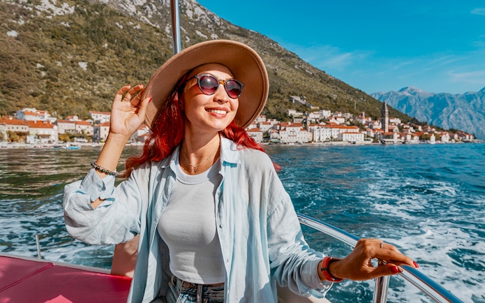 Female guest on a boat trip in Kotor Bay with coastal town view.