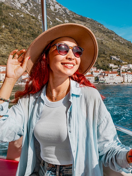 Female guest on a boat trip in Kotor Bay with coastal town view.