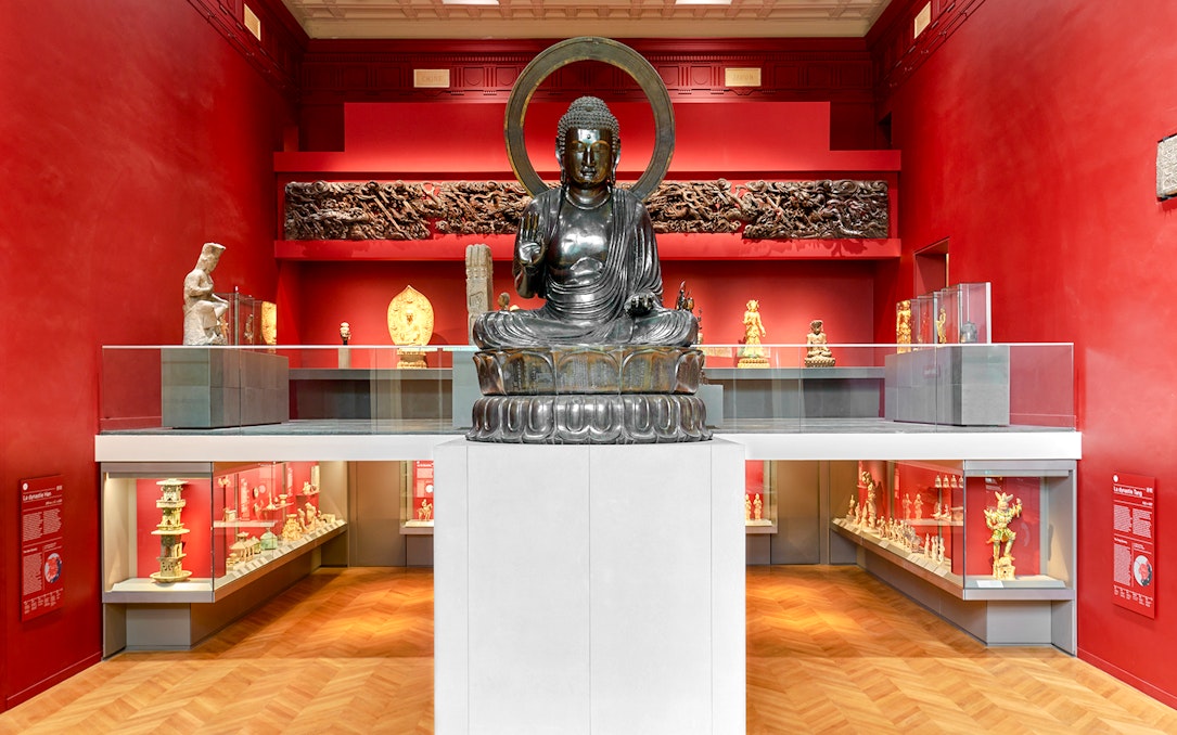 Buddha statue in Cernuschi Museum, Paris, surrounded by Asian art exhibits.