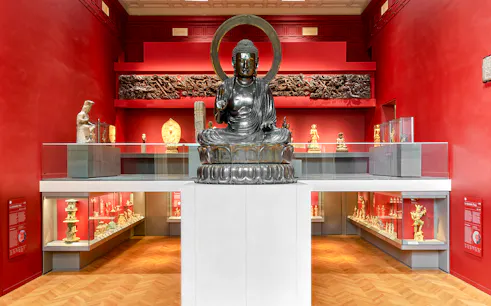 Buddha statue in Cernuschi Museum, Paris, surrounded by Asian art exhibits.