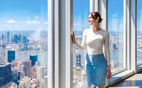 Person enjoying city view from Empire State Building observatory in New York City.