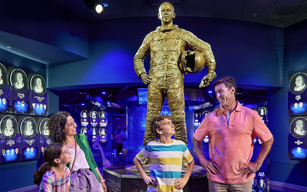 Family admiring astronaut statue at Heroes and Legends exhibit, Kennedy Space Center.