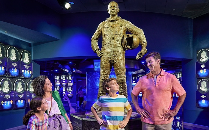 Family admiring astronaut statue at Heroes and Legends exhibit, Kennedy Space Center.