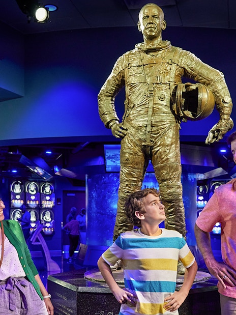 Family admiring astronaut statue at Heroes and Legends exhibit, Kennedy Space Center.