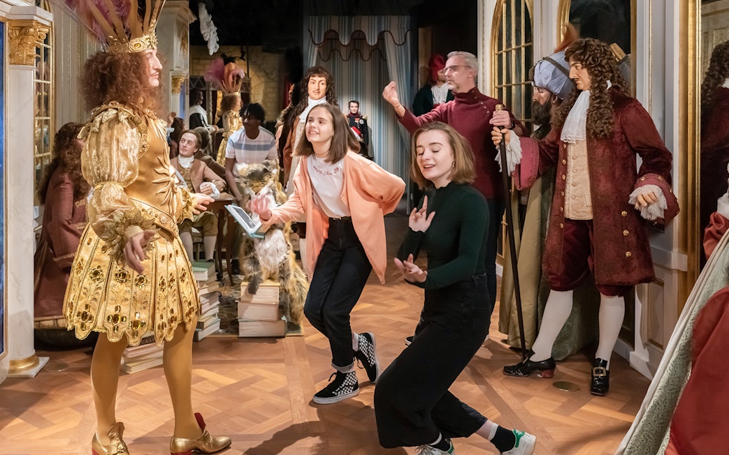Visitors interacting with wax figures in historical costumes at Grévin Paris Wax Museum.