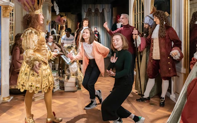Visitors interacting with wax figures in historical costumes at Grévin Paris Wax Museum.
