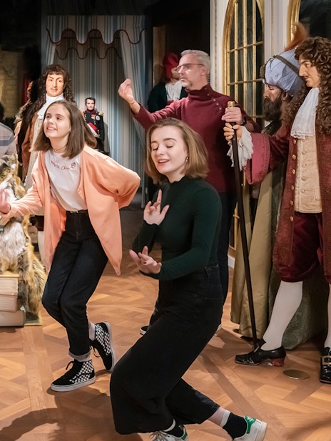 Visitors interacting with wax figures in historical costumes at Grévin Paris Wax Museum.
