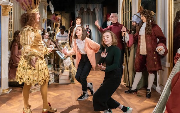 Visitors interacting with wax figures in historical costumes at Grévin Paris Wax Museum.