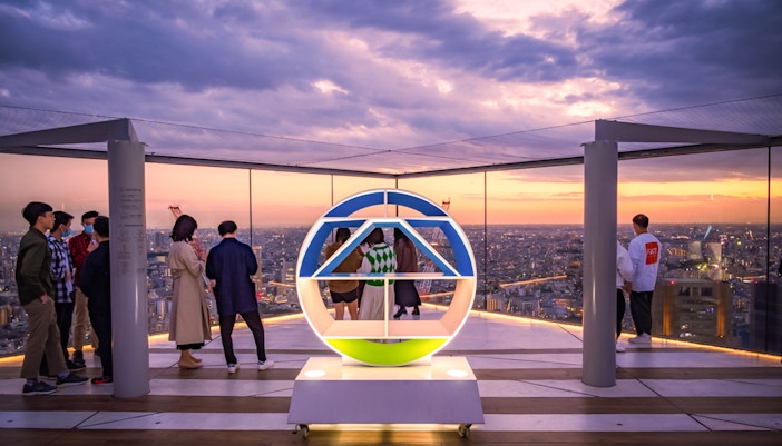 Tourists enjoying sunset views from Shibuya Sky Deck in Tokyo.